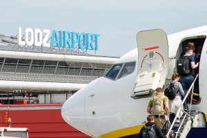 Pasażerowie wchodzą do samolotu. W tle napis na budynku terminala Lodz Airport. Pasażerowie wchodzą do samolotu. W tle napis na budynku terminala Lodz Airport.