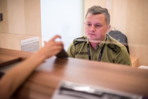 Funkcjonariusz patrzy na dokument, który trzyma podróżny. Funkcjonariusz patrzy na dokument, który trzyma podróżny.