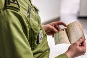 Funkcjonariusz SG trzymający paszport 