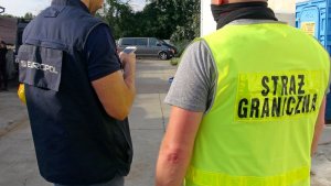 Funkcjonariusze Europolu i Straży Granicznej stojący tyłem. Funkcjonariusze Europolu i Straży Granicznej stojący tyłem.