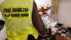 Funkcjonariusz SG trzyma karton z saszetkami. Funkcjonariusz SG trzyma karton z saszetkami.