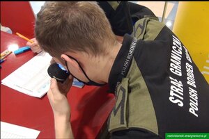 Funkcjonariusz SG sprawdza autentyczność dokumentu 