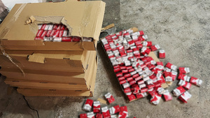 Widoczne paczki papierosów w rozdartym kartonie oraz leżące na podłodze. Widoczne paczki papierosów w rozdartym kartonie oraz leżące na podłodze.