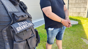Zatrzymany stoi z rękami w kajdankach. Zatrzymany stoi z rękami w kajdankach.