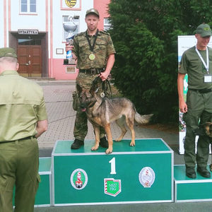 Sierż. SG Adrian Smolak z psem Fantą stoi na podium. Sierż. SG Adrian Smolak z psem Fantą stoi na podium.