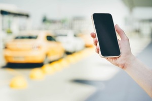 Telefon GSM trzymany w ręku na tle samochodu osobowego 