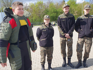 Po lewej stronie uczeń przebrany w kombinezon pirotechniczny. Obok stoją jego koledzy. Po lewej stronie uczeń przebrany w kombinezon pirotechniczny. Obok stoją jego koledzy.