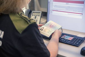 Zbliżenie na paszport, który trzyma w rękach funkcjonariuszka. Zbliżenie na paszport, który trzyma w rękach funkcjonariuszka.