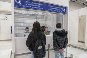 Podróżni stoją przed kabiną kontroli granicznej. W środku funkcjonariusze sprawdzają dokumenty. Podróżni stoją przed kabiną kontroli granicznej. W środku funkcjonariusze sprawdzają dokumenty.