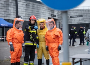 Trzech mężczyzn ubranych w kombinezony ochronne słucha strażaka. Fot. Bartosz Kałużny. Trzech mężczyzn ubranych w kombinezony ochronne słucha strażaka. Fot. Bartosz Kałużny.