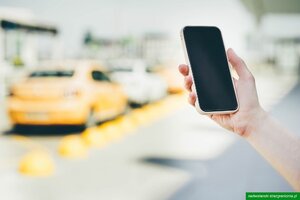 Telefon trzymany w dłoni.W tle samochody. Telefon trzymany w dłoni.W tle samochody.
