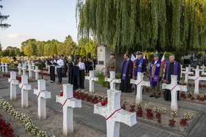 Widok ogólny na cmentarz. Wśród krzyży stoi młodzież, duchowni. W tyle widać Pomnik z posterunkiem honorowym. Widok ogólny na cmentarz. Wśród krzyży stoi młodzież, duchowni. W tyle widać Pomnik z posterunkiem honorowym.