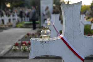Palący się znicz stoi na krzyżu. Palący się znicz stoi na krzyżu.