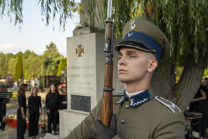 Na pierwszym planie stoi funkcjonariusz w historycznym mundurze. W tle Pomnik Żołnierzom Poległym w Obronie Ojczyzny.. Na pierwszym planie stoi funkcjonariusz w historycznym mundurze. W tle Pomnik Żołnierzom Poległym w Obronie Ojczyzny..