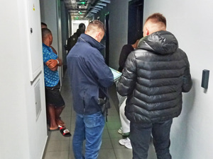 Funkcjonariusze stoją na korytarzu, patrzą w dokumentację. Funkcjonariusze stoją na korytarzu, patrzą w dokumentację.