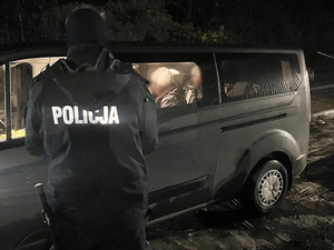 Policjant stoi przy samochodzie. W środku siedzą cudzoziemcy. Policjant stoi przy samochodzie. W środku siedzą cudzoziemcy.