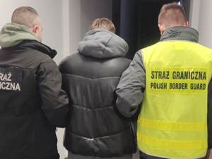 Funkcjonariusze prowadzą zatrzymanego. Funkcjonariusze prowadzą zatrzymanego.