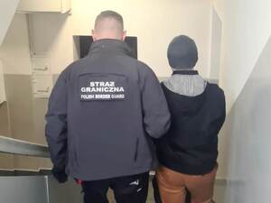 Funkcjonariusz prowadzi zatrzymanego po schodach. Funkcjonariusz prowadzi zatrzymanego po schodach.