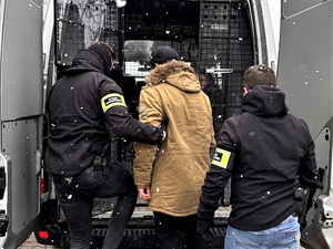 Funkcjonariusze SG wprowadzają zatrzymanego mężczyznę do pojazdu 