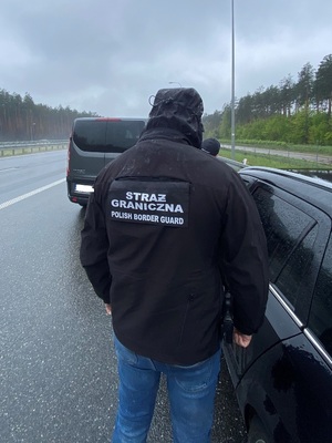Funkcjonariusz Straży Granicznej odwrócony tyłem podczas kontoli na drodze 