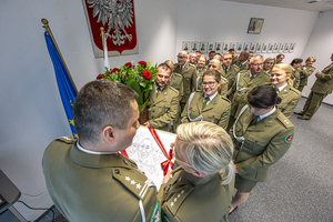 Funkcjonariusze wręczają upominek i kwiaty. Funkcjonariusze wręczają upominek i kwiaty.