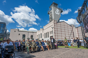Ogólny widok na uczestników uroczystości siedzących na placu przed Muzeum Powstania Warszawskiego. Ogólny widok na uczestników uroczystości siedzących na placu przed Muzeum Powstania Warszawskiego.