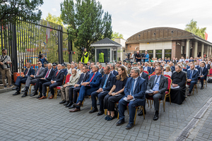 Zaproszeni goście siedzą na krzesłach przed Budynkiem PWPW. Zaproszeni goście siedzą na krzesłach przed Budynkiem PWPW.