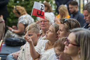 Dziewczynka patrzy na trzymaną w dłoni biało-czerwoną flagę z symbolem Polski Walczącej. Dziewczynka patrzy na trzymaną w dłoni biało-czerwoną flagę z symbolem Polski Walczącej.
