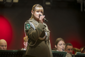 Solistka orkiestry śpiewa, w ręku trzyma mikrofon. Solistka orkiestry śpiewa, w ręku trzyma mikrofon.
