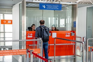 Mężczyzna stoi przy kabinie kontrolerskiej. W środku siedzą dwie funkcjonariuszki. Mężczyzna stoi przy kabinie kontrolerskiej. W środku siedzą dwie funkcjonariuszki.