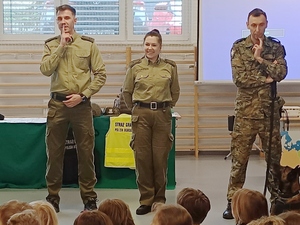 Troje funkcjonariuszy stoi podczas spotkania. Na podłodze leży pies służbowy. Troje funkcjonariuszy stoi podczas spotkania. Na podłodze leży pies służbowy.