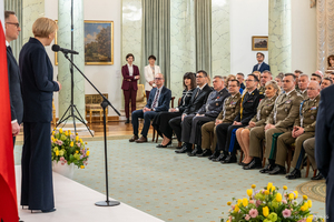 Przy mikrofonie stoi Pani Agata Kornhauser-Duda. W tle siedzą zaproszeni goście. Przy mikrofonie stoi Pani Agata Kornhauser-Duda. W tle siedzą zaproszeni goście.