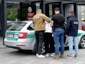 Funkcjonariusze wprowadzają zatrzymanego do samochodu. Funkcjonariusze wprowadzają zatrzymanego do samochodu.
