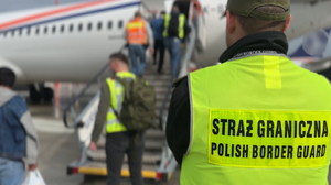 Funkcjonariusz w żółtej kamizelce stoi przy schodach, po których cudzoziemcy wchodzą do samolotu. Funkcjonariusz w żółtej kamizelce stoi przy schodach, po których cudzoziemcy wchodzą do samolotu.