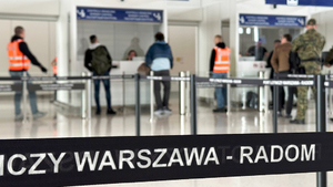 U dołu taśma z napisem Warszawa-Radom. W tle trwa odprawa paszportowa. U dołu taśma z napisem Warszawa-Radom. W tle trwa odprawa paszportowa.