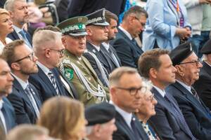 Uczestnicy uroczystości siedzą na krzesłach. Uczestnicy uroczystości siedzą na krzesłach.