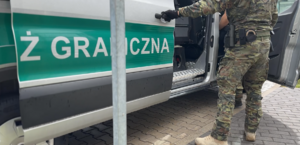 Funkcjonariusz wprowadza cudzoziemca do pojazdu służbowego. Funkcjonariusz wprowadza cudzoziemca do pojazdu służbowego.