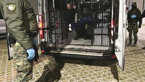 Cudzoziemcy siedzą w pojeździe służbowym. Na zewnątrz stoję funkcjonariusze. Cudzoziemcy siedzą w pojeździe służbowym. Na zewnątrz stoję funkcjonariusze.