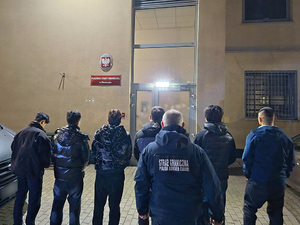 Mężczyźni stoją przed wejściem do Placówki Straży Granicznej. Mężczyźni stoją przed wejściem do Placówki Straży Granicznej.