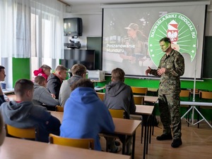 Funkcjonariusz prowadzi zajęcia z uczniami w sali lekcyjnej. Funkcjonariusz prowadzi zajęcia z uczniami w sali lekcyjnej.