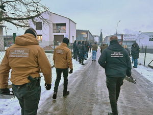 Funkcjonariusze idą w stronę budynków. Funkcjonariusze idą w stronę budynków.