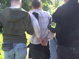 Funkcjonariusze prowadzą zatrzymanego. Funkcjonariusze prowadzą zatrzymanego.